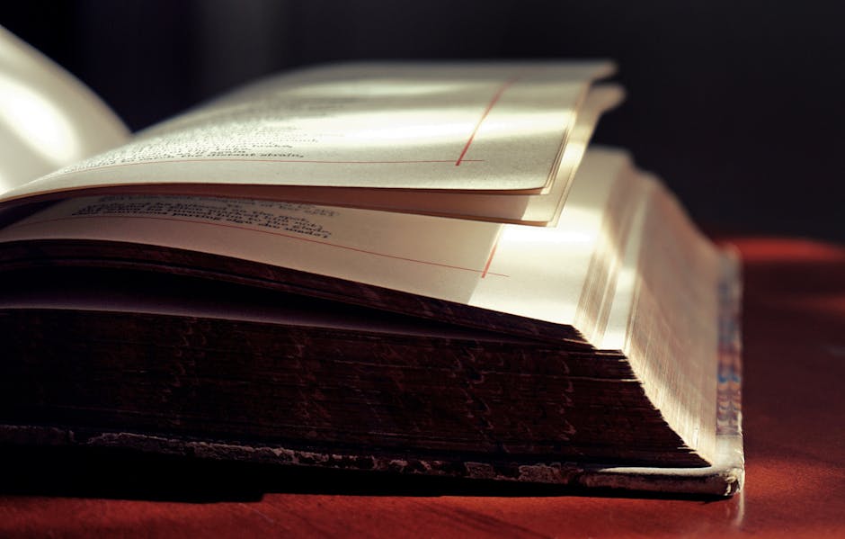 Artistic close-up of an open hardcover book in soft lighting, highlighting the texture of the pages.
