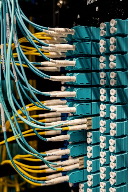 Similar colorful rubber cables with connectors in fiber optical switch sockets in sunlight